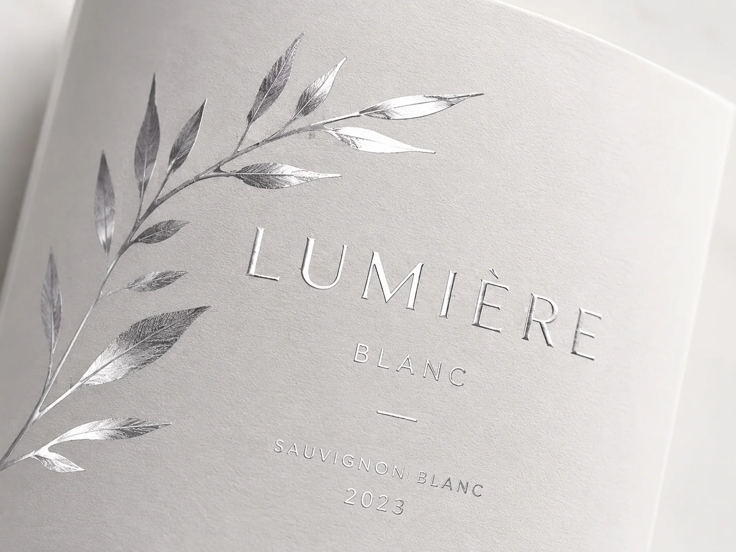 Luxury Lumière Blanc wine label with intricate silver cold foil botanical leaf artwork on textured paper